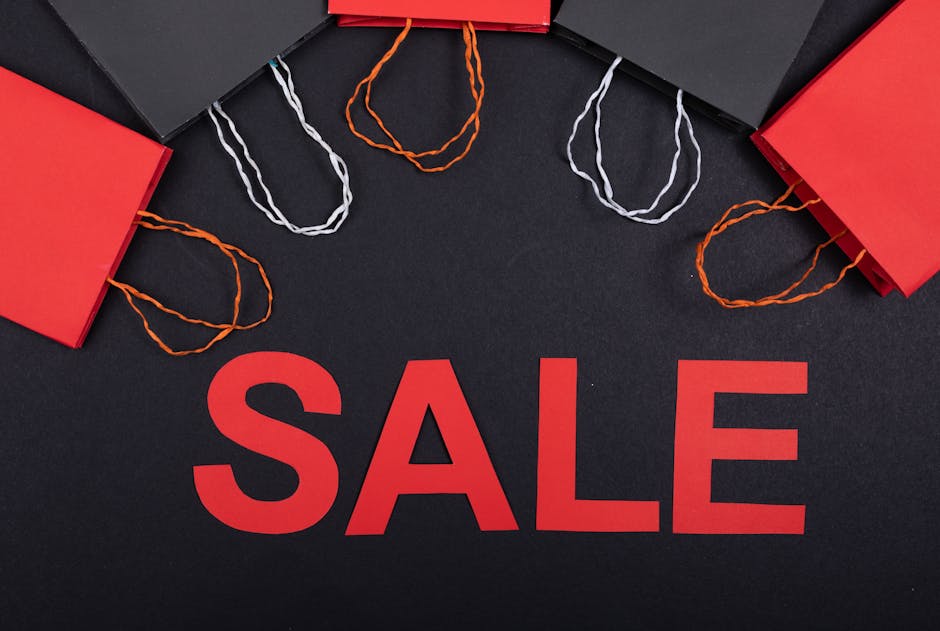 Top view of red and black shopping bags with sale text on a black background.