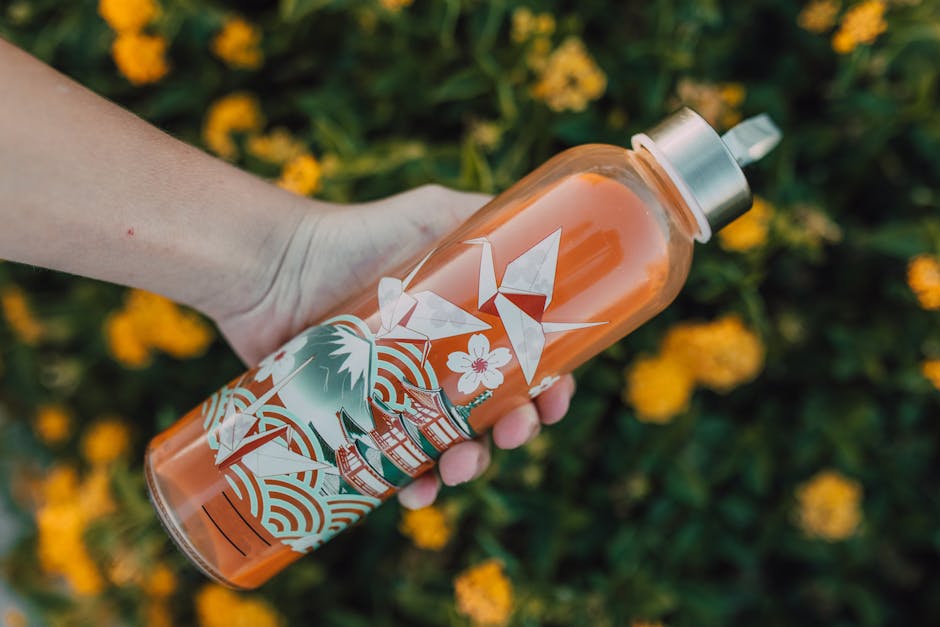 A person holding a colorful tumbler with floral and geometric designs outdoors.