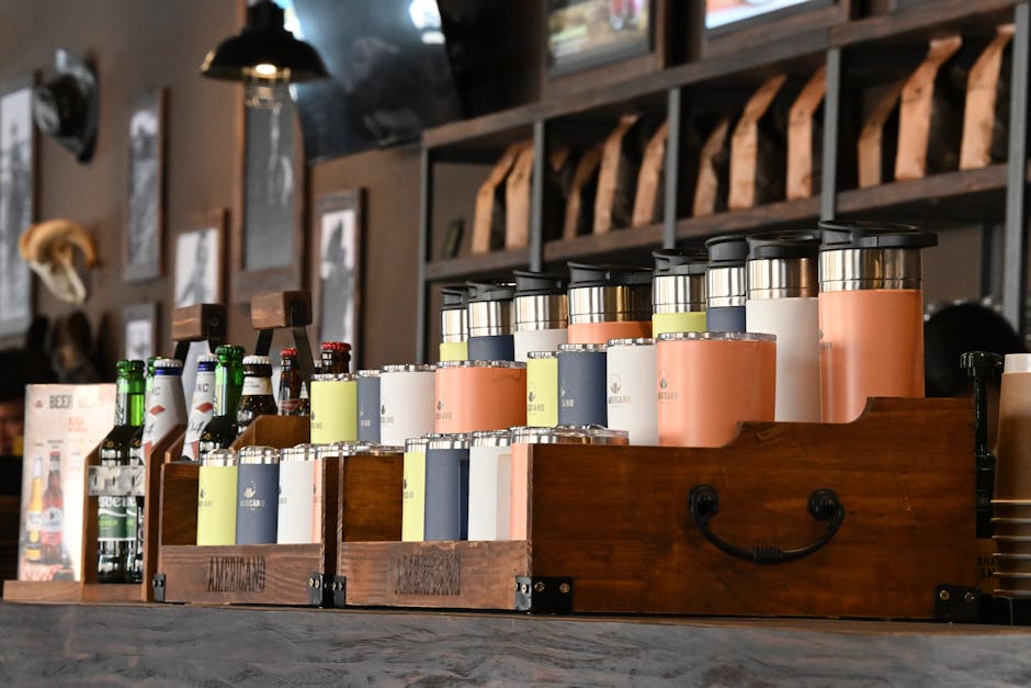 Modern coffee shop interior featuring assorted bottles and thermoses on a rustic wooden bar.