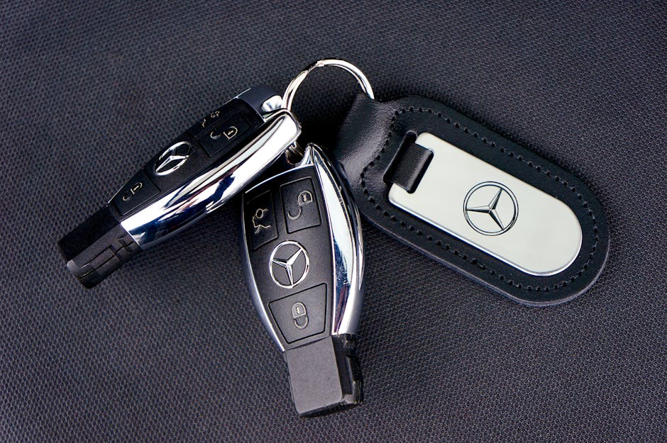Close-up of Mercedes-Benz car keys with a leather keychain on dark fabric background.