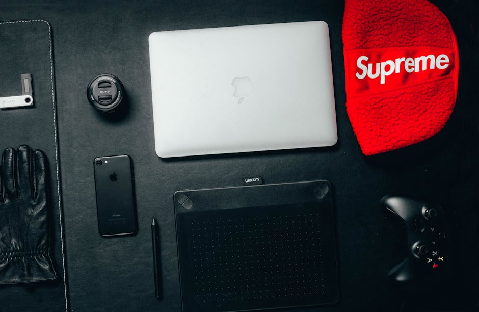 Flat lay of a modern workspace featuring a laptop, smartphone, tablet, and accessories on a black surface.