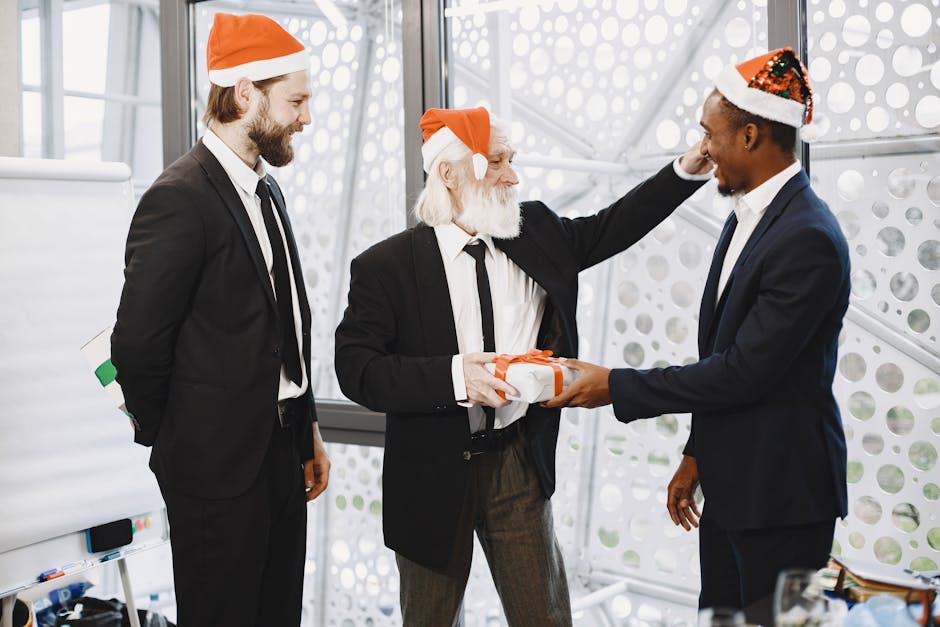 Three colleagues in suits exchange Christmas gifts in a festive office setting.