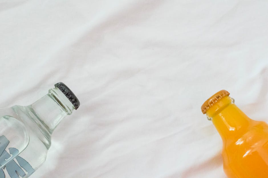 Two bottles with beverages on a clean white sheet, perfect for product advertising backgrounds.