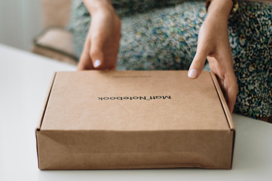 A person holding a closed craft notebook box indoors, focusing on packaging.