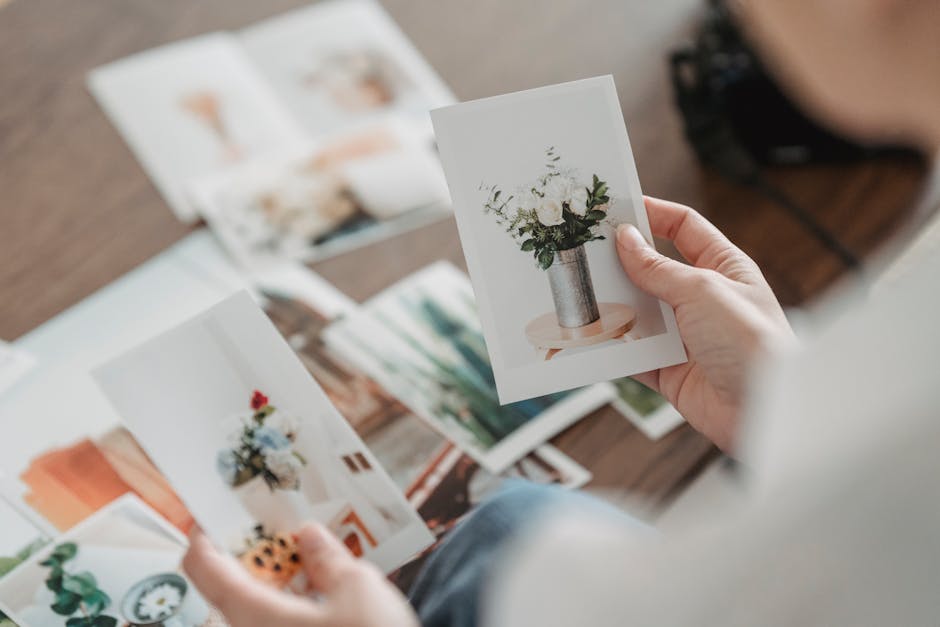 From above of crop anonymous person comparing photos of floral bouquets at desk on blurred background