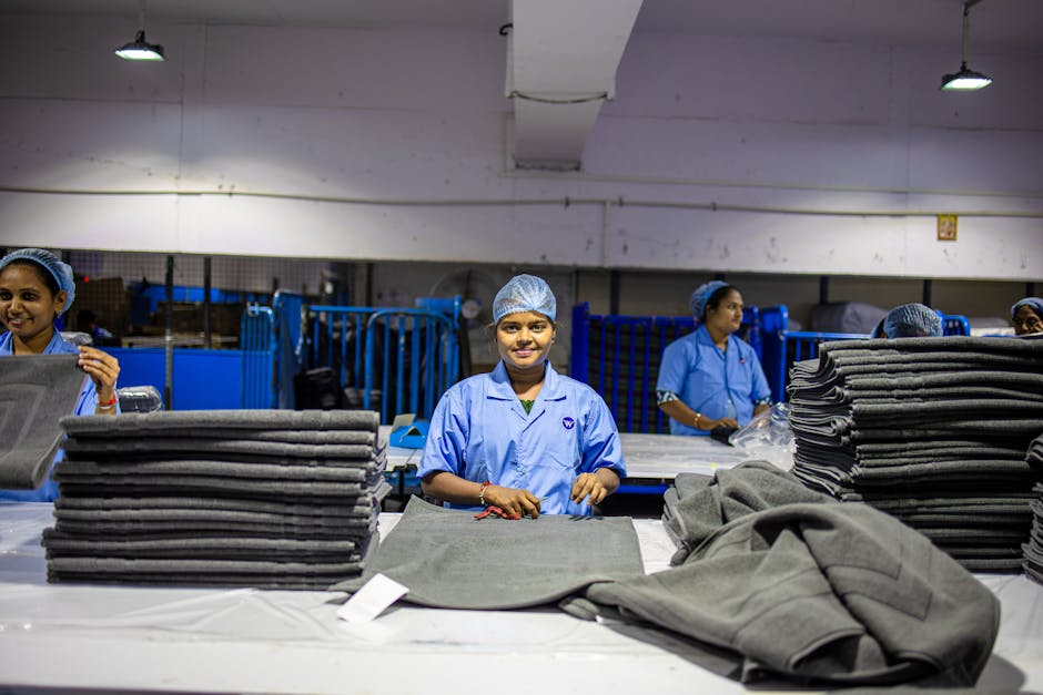 Smiling workers in a textile factory sorting large fabric stacks efficiently.