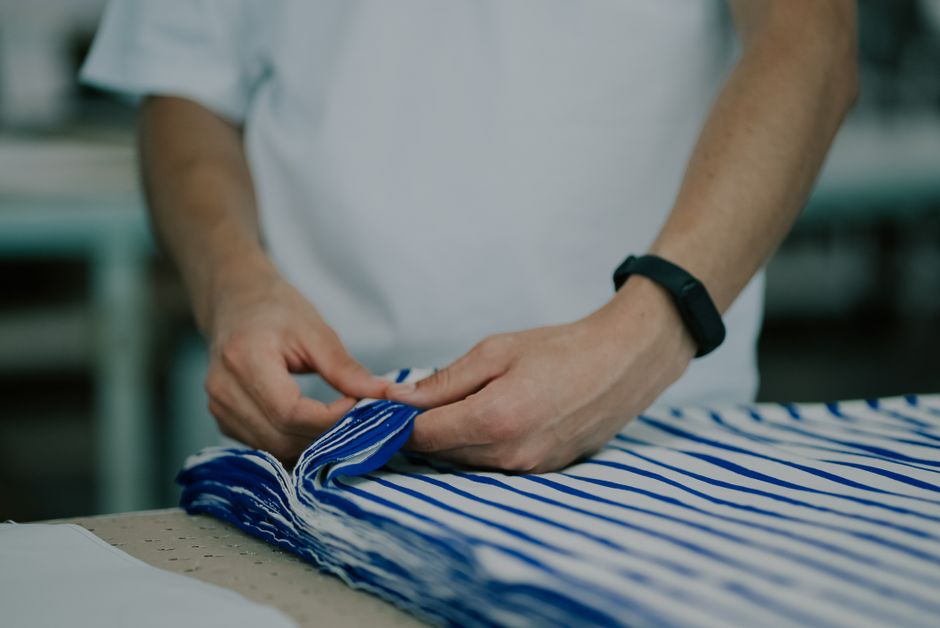 Close-up of hands holding striped fabric indoors, highlighting textile details.